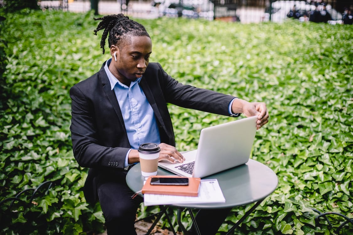 Free Concentrated ethnic businessman using laptop in park Stock Photo