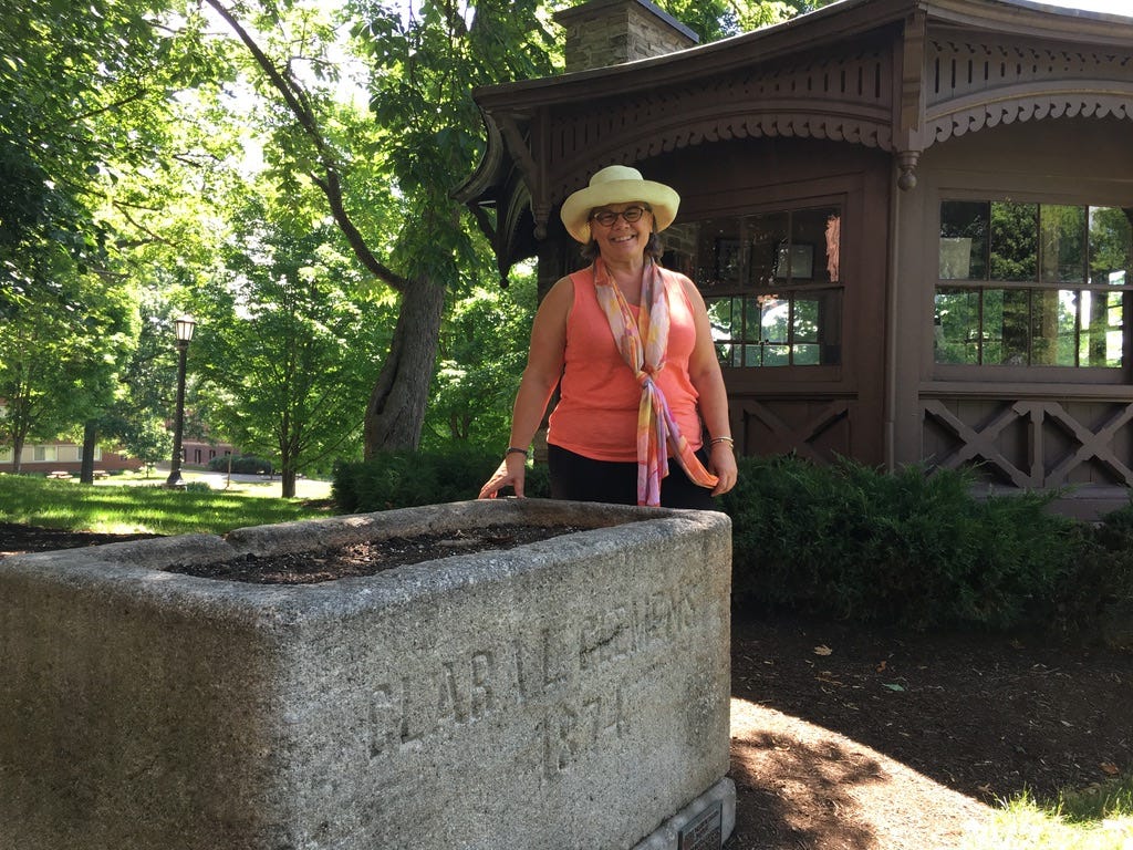 woman standing between a planter bearing Clara L. Clemens name and Mark Twain's octagonal writing study