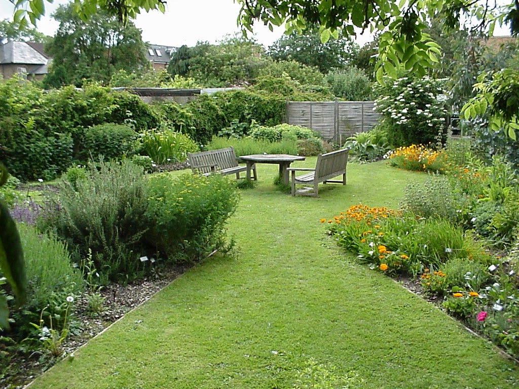 A herb garden with many border plants and shrubs and seats too