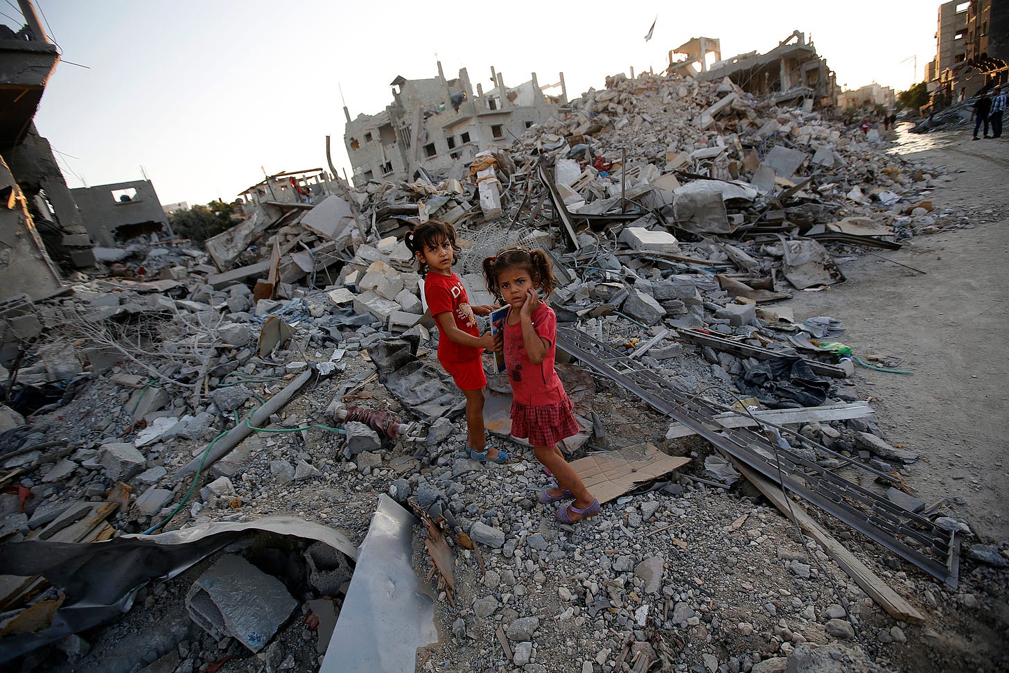 Two small Palestinian sisters standing inthe shocking afermath of heavy artillery and bombing.