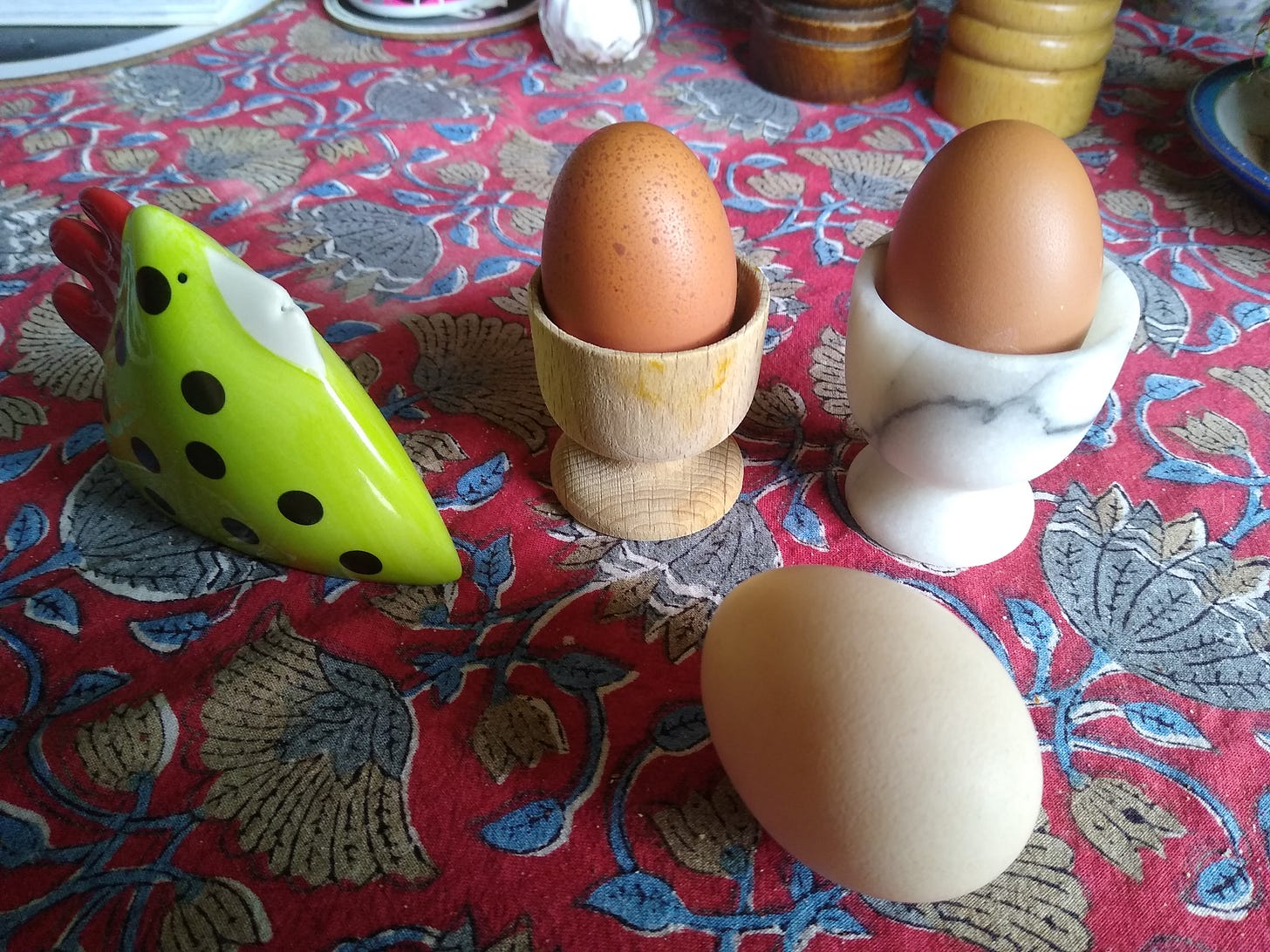 A photograph of three eggs and a salt shaker in the shape of a green spotty bird.