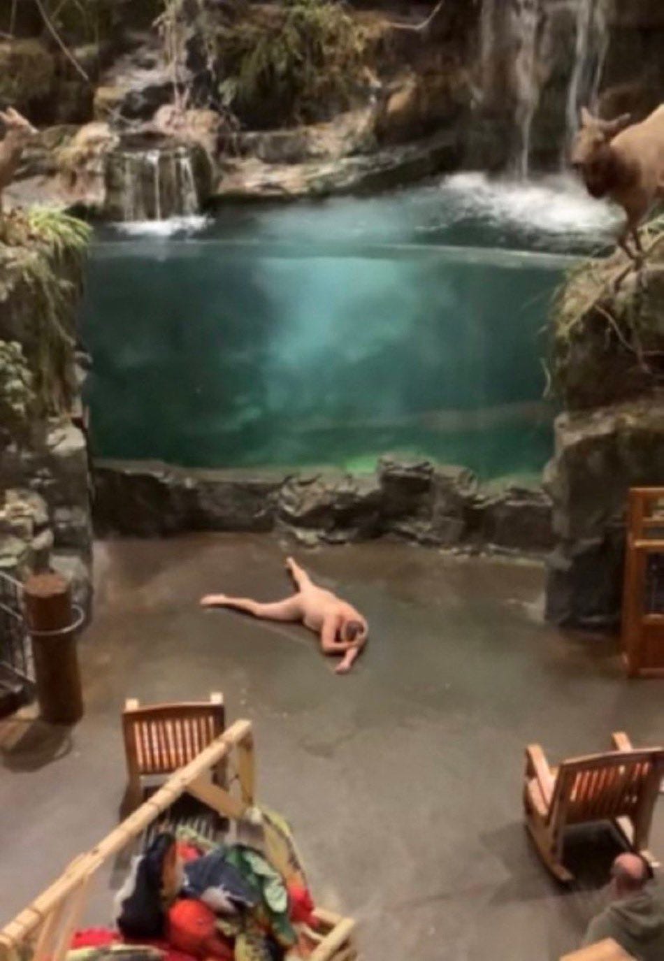 Nude guy laying on the floor in front of the Bass Pro Shop aquarium.