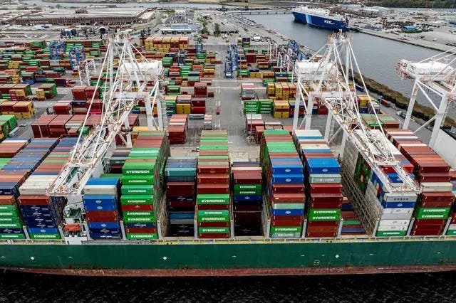 A cargo ship moored to the pier at the port of Baltimore in the US. Hundreds of containers can be seen, many of which are branded Evergreen. Three large cranes can also be seen.