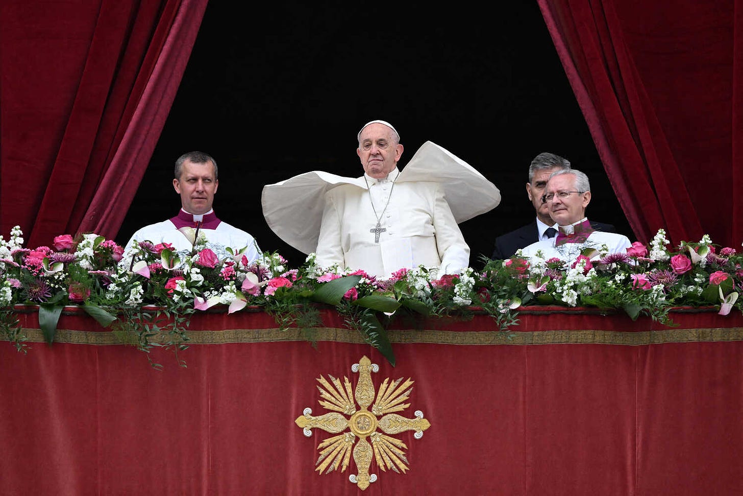 Pope Francis, flanked by two members of the clergy, gazes down.