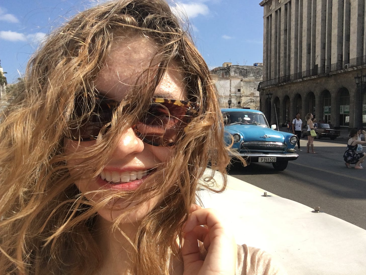 A blonde woman with curly hair in the back of a 1957 Chevy Bel Air in Havana