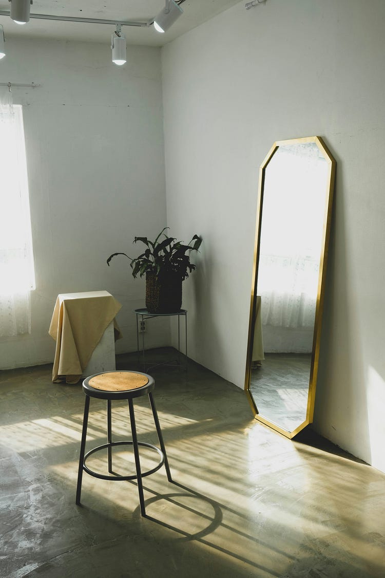 A long mirror with a small stool in front.