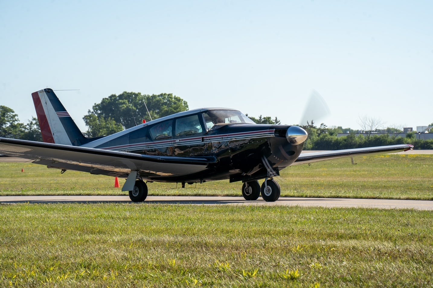 Photograph of a single propeller plane on a runway, surrounded by grass.