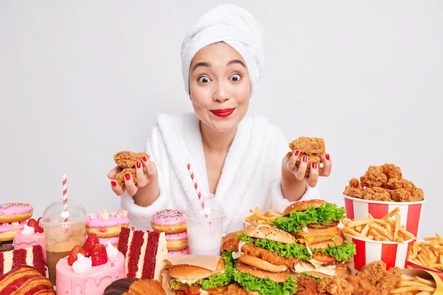 Surprised cheerful asian woman focused at camera surrounded by fast food