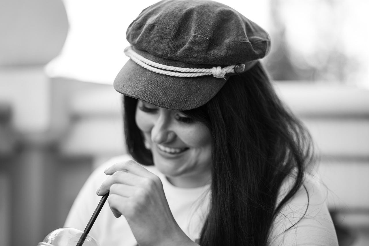 A young woman smiles as she drinks her coffee. A young woman smiles as she drinks her coffee.