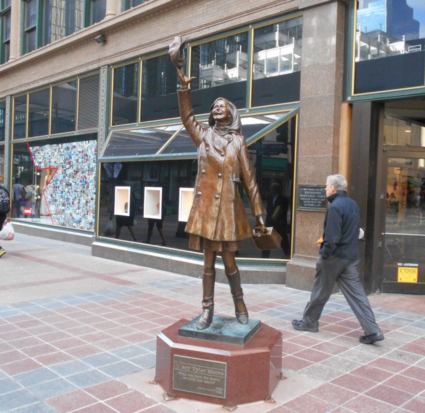 Photo of bronze statue depicting Mary Tyler Moore tossing her cap in the air, downtown Minneapolis