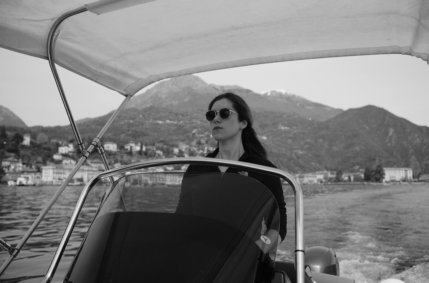 black and white photo of Kayla Stark driving a boat on Lake Como
