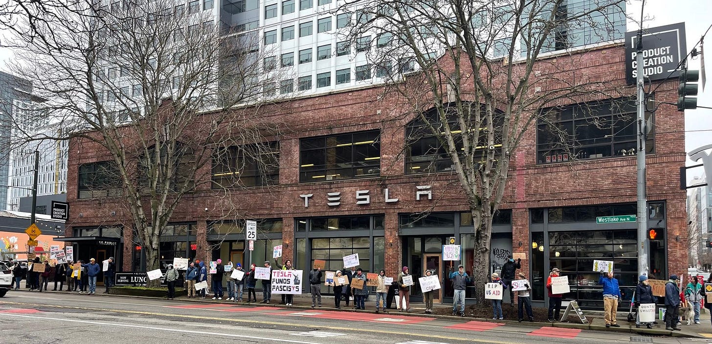 More than 60 people protest outside of a Tesla Dealership in Seattle.