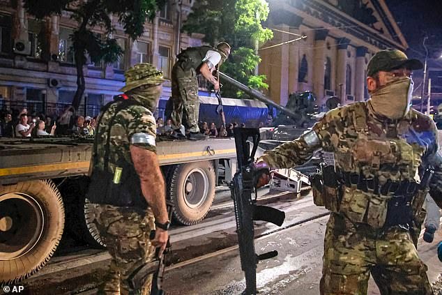 Members of the Wagner Group military company guard an area as other load their tank onto a truck on a street in Rostov-on-Don, Russia, Saturday, June 24, 2023, prior to leaving an area at the headquarters of the Southern Military District