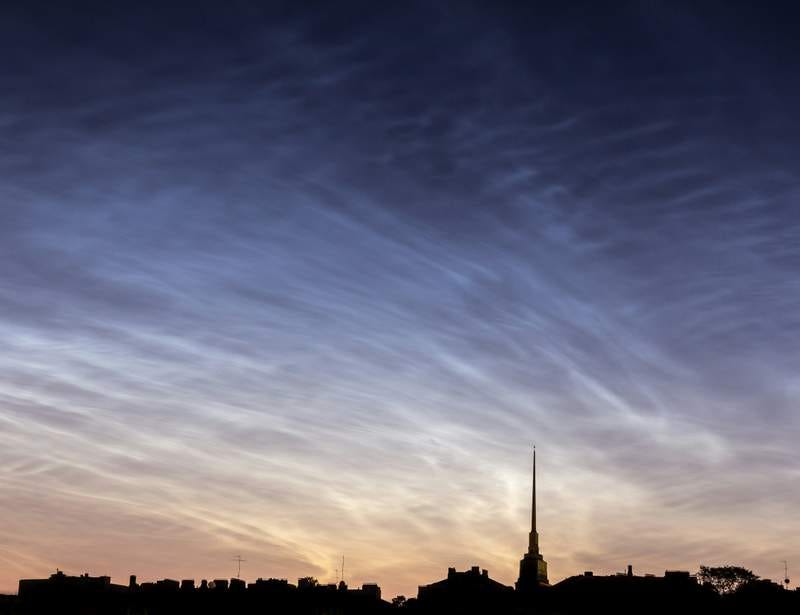 Photo of a particularly beautiful dusk with a partly clouded blue-purple sky shading to white over the part-silhouette of a town.