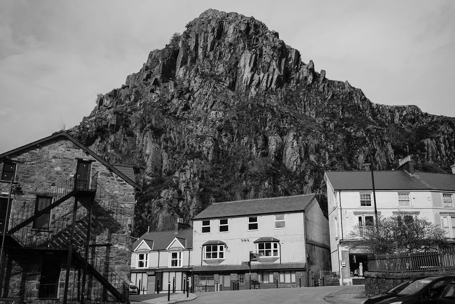 Black and white photograph of a jagged rocky mountain towering over white houses