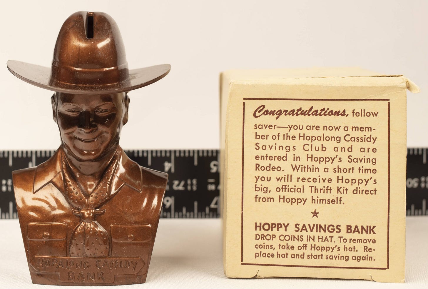 A bust of Hopalong Cassidy is a kiddie bank, with a coin slot on top of his cowboy hat. Accompanying copy on the product box reads: “Congratulations, fellow saver-you are now a member of the Hopalong Cassidy Savings Club and are entered in Hoppy's Saving Rodeo. Within a short time you will receive Hoppy's big, official Thrift Kit direct from Hoppy himself. HOPPY SAVINGS BANK. DROP COINS IN HAT. To remove coins, take off Hoppy's hat. Replace hat and start saving again.”