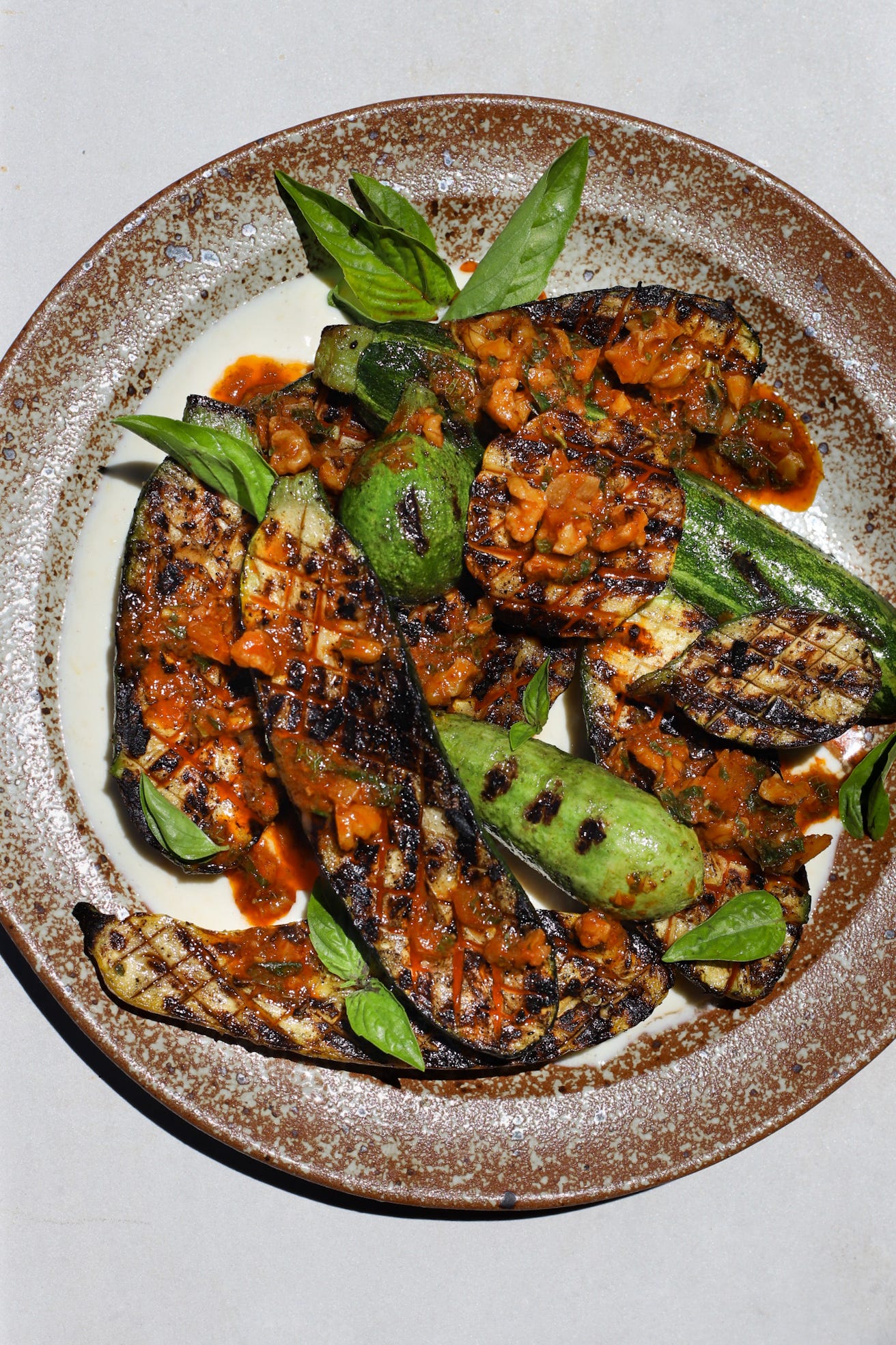 Plate of grilled zucchini with harissa-walnut dressing and basil