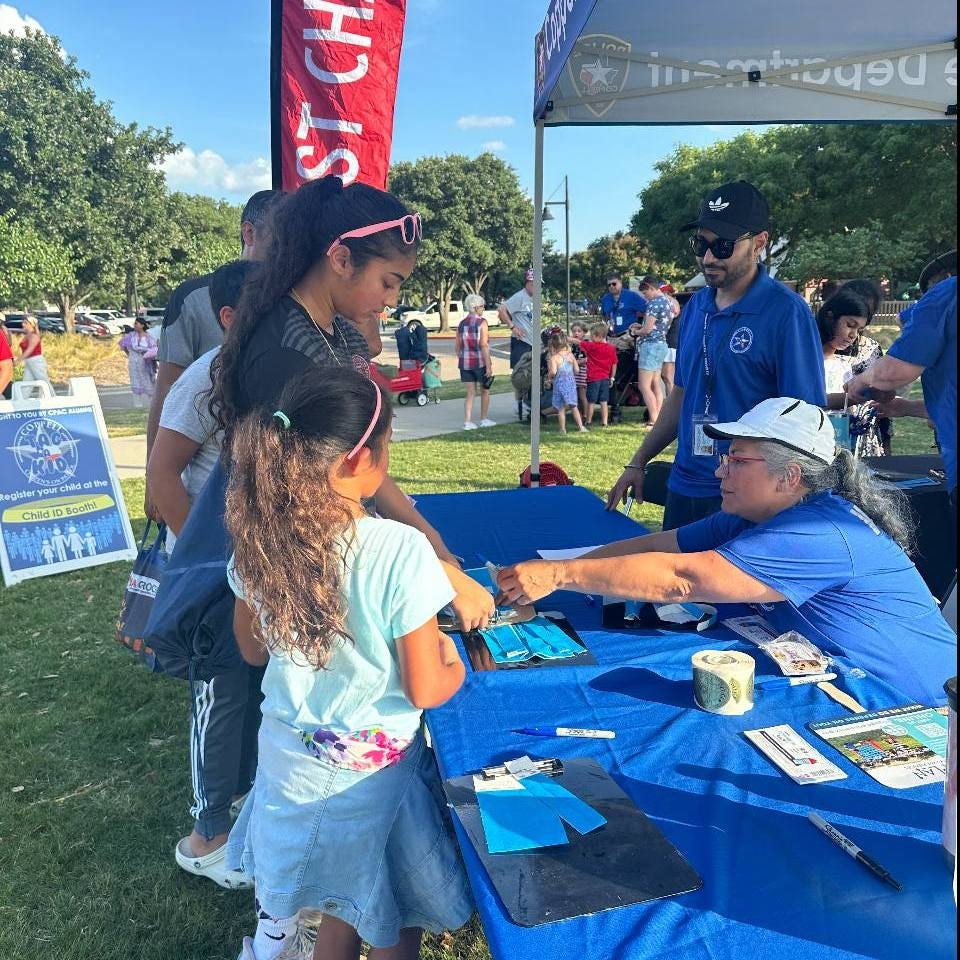 A volunteer places a wristband on a child at a park