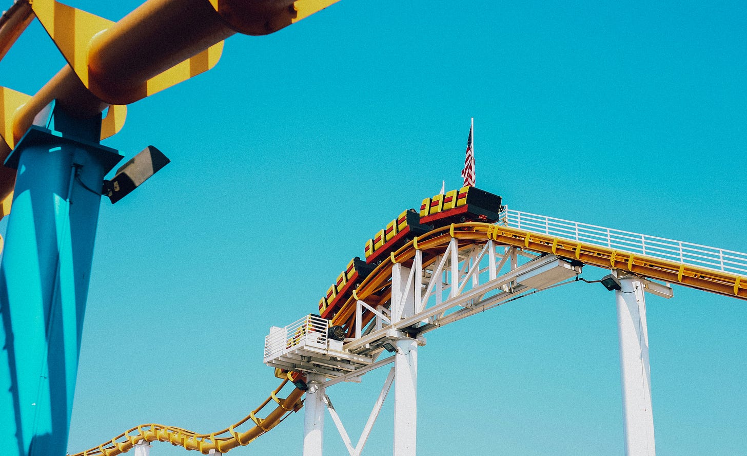 yellow and red rollercoaster suspended high in the air against blue sky