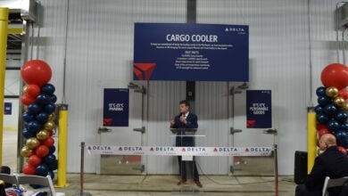 A speaker celebrates the opening of Delta Cargo's new cold storage facility with balloons next to the stage.