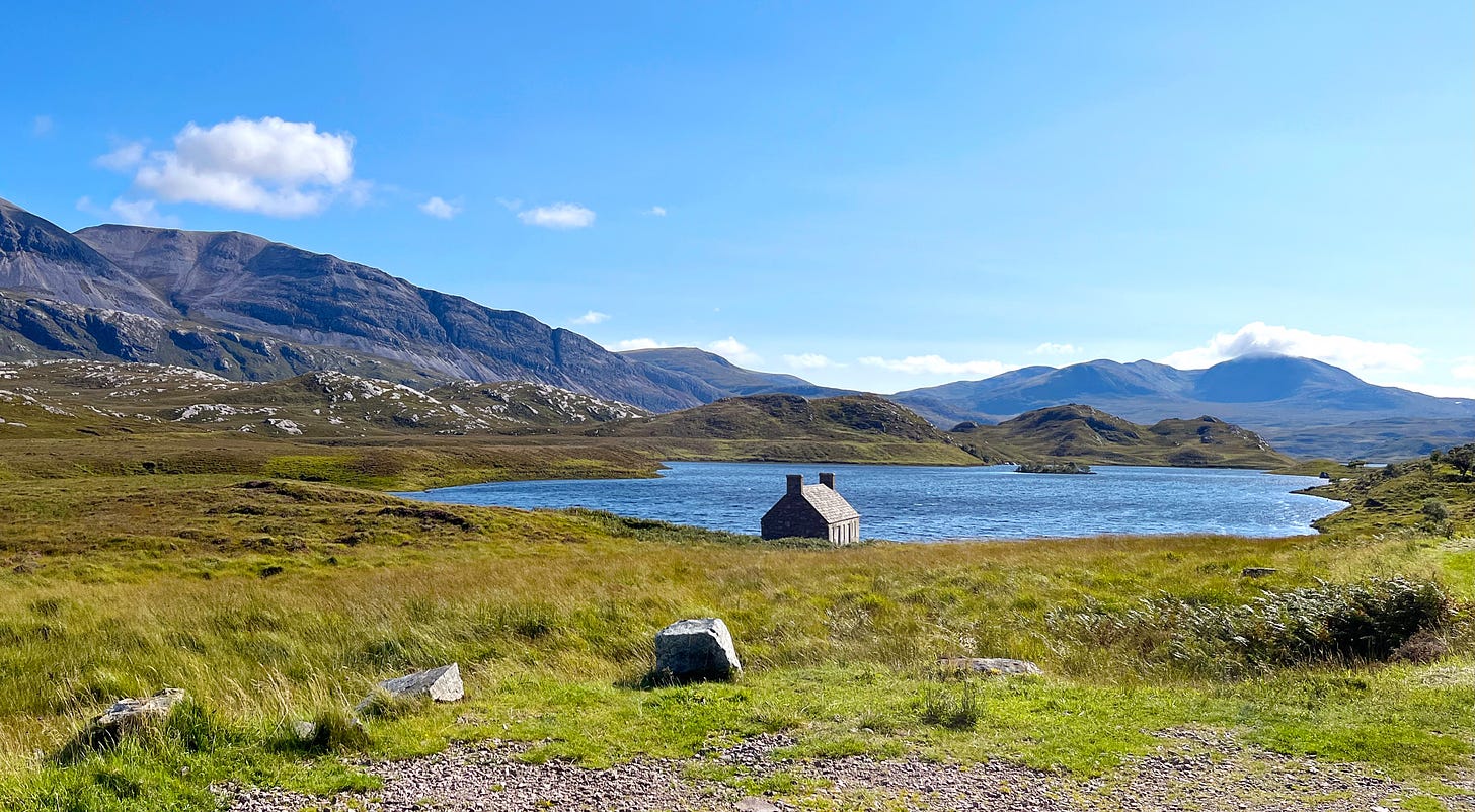 hills rise either side of moorland with a deserted stone house on the loch bank