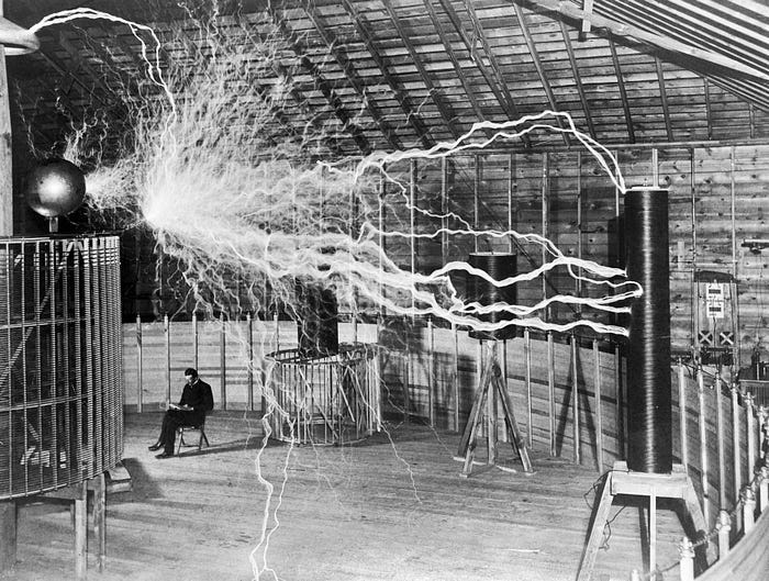Tesla sitting next to his “magnifying transmitter” generating millions of volts — promotional stunt