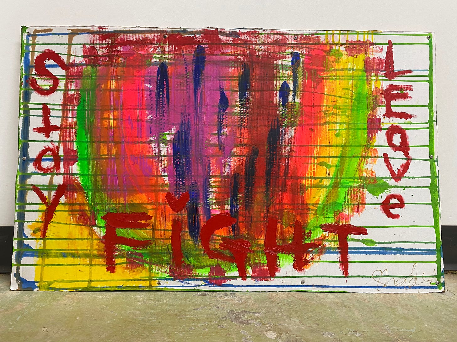A finger painting on cardboard featuring the words "Stay, fight, leave" and a watermelon with a rainbow rind.