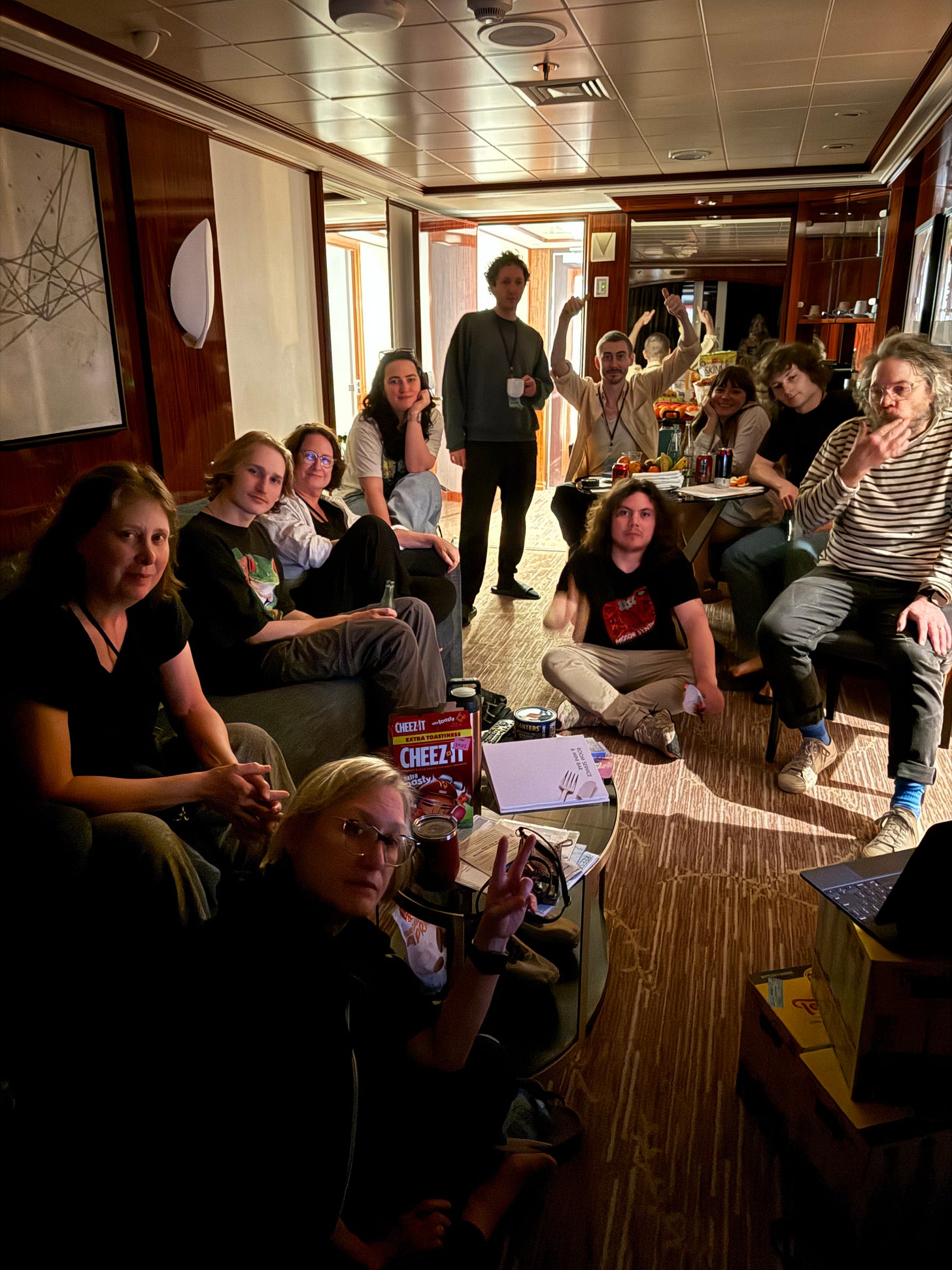 Several people watch the Oscars on an iPad in a dimly lit cruise ship stateroom.