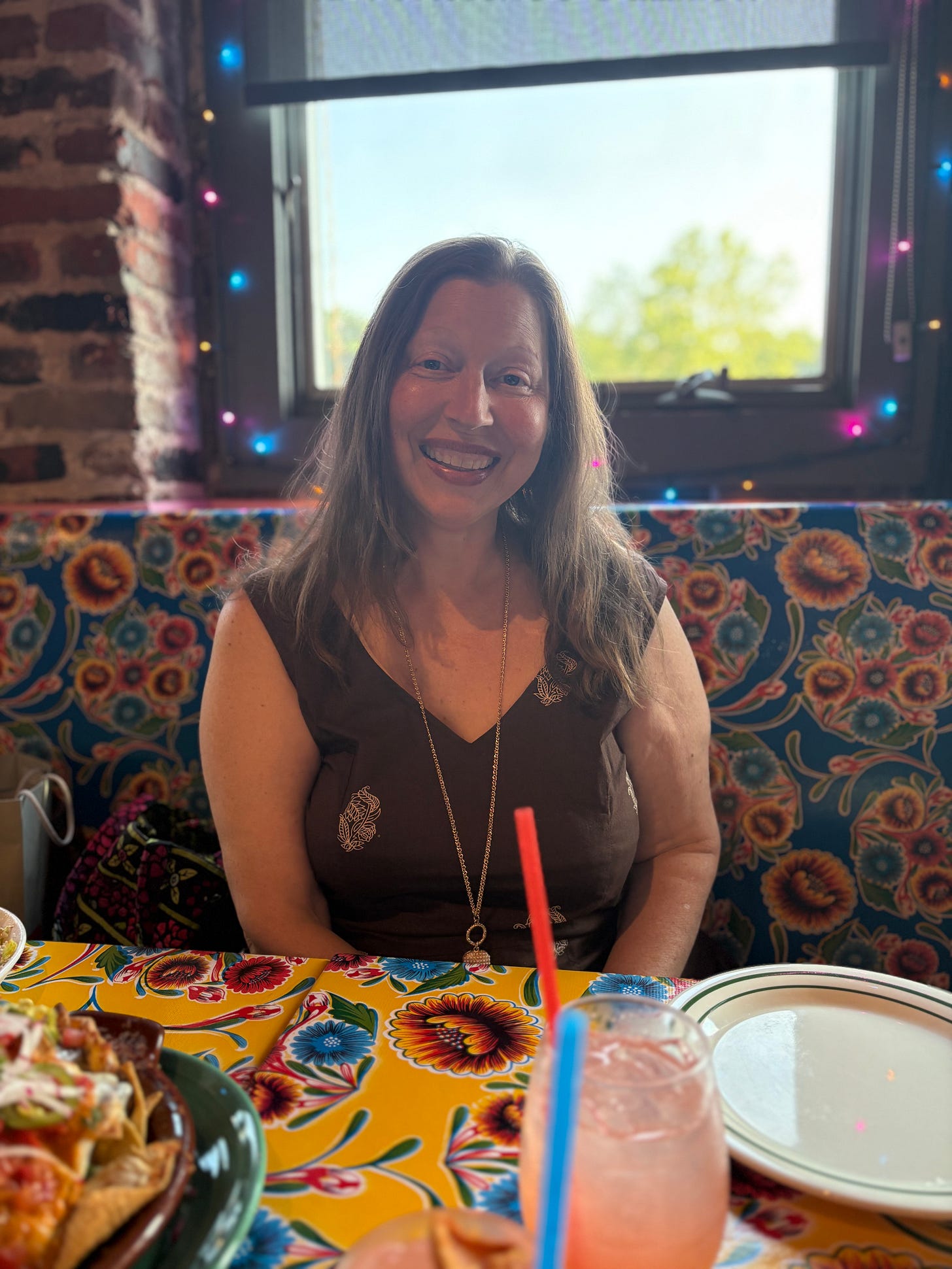 Gabrielle sits at a table smiling, surrounded by twinkling lights