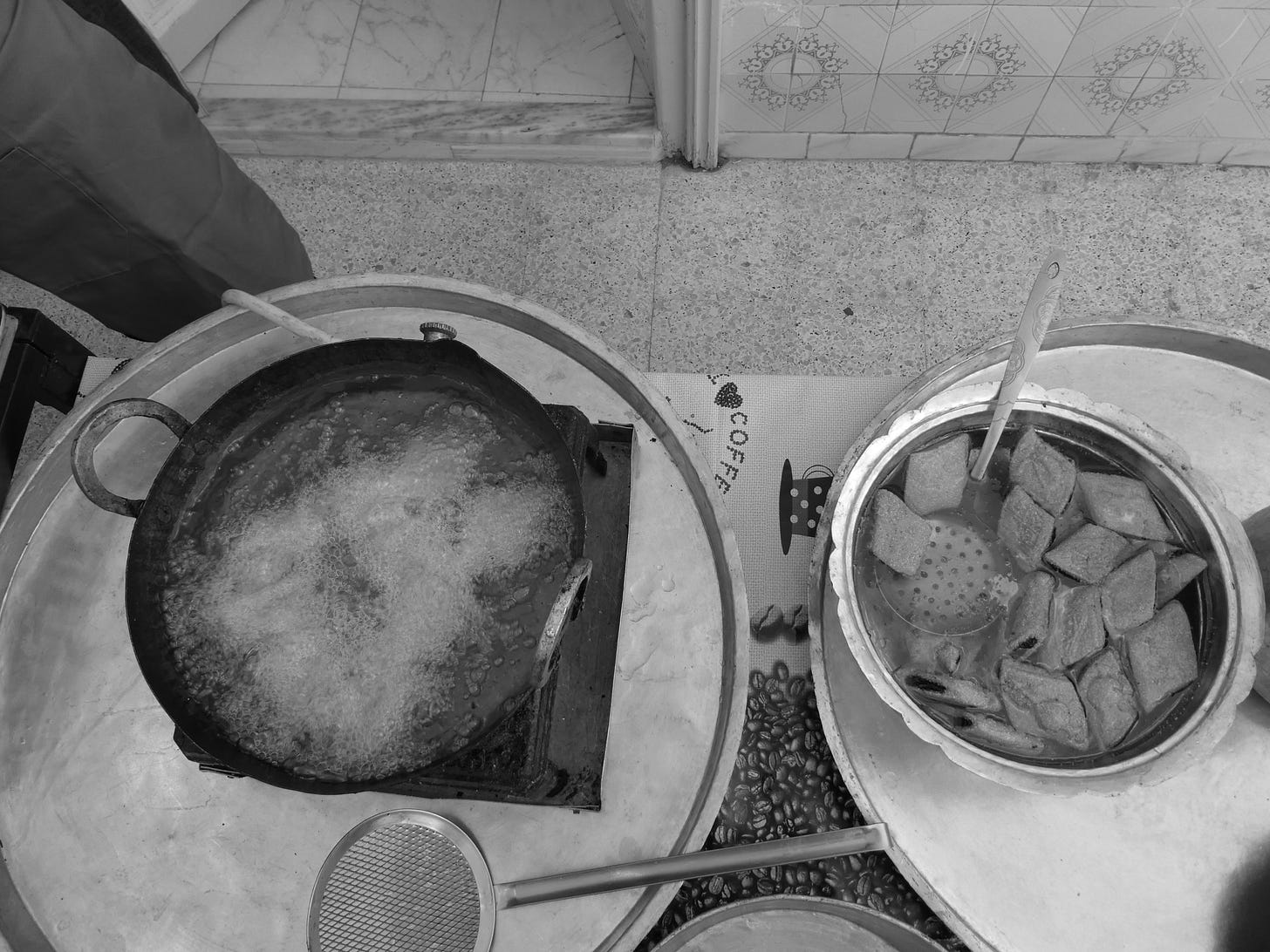 A birds eye view of makroudh frying on the left and soaking in sugar syrup on the right