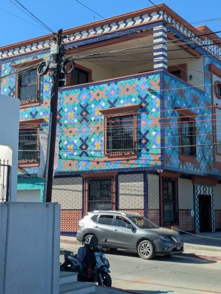 a three story building in a town, covered with brightly colored tile in assorted patterns