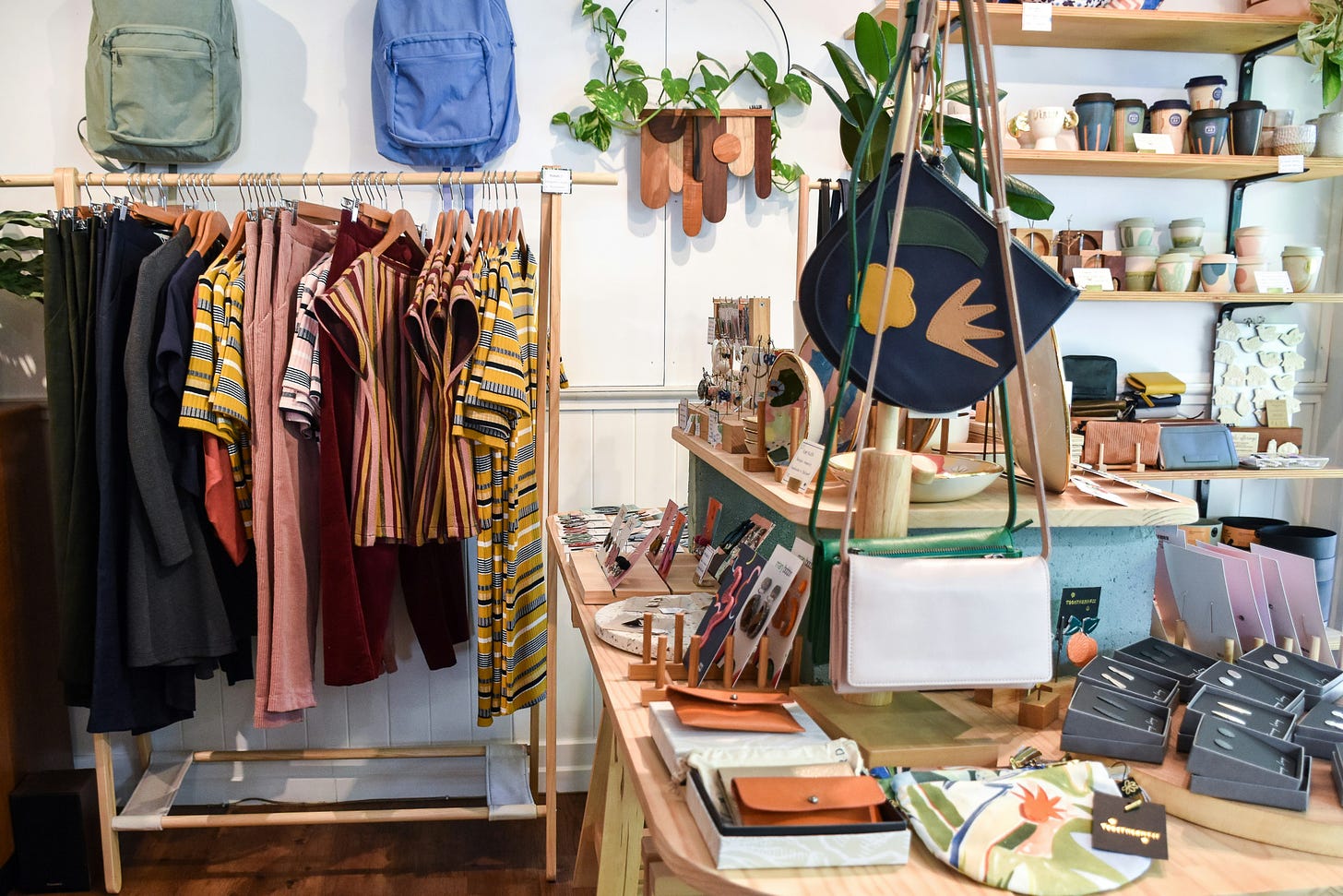 medium shot of boutique interior with colorful clothes, backpacks, and accessories displayed for sale