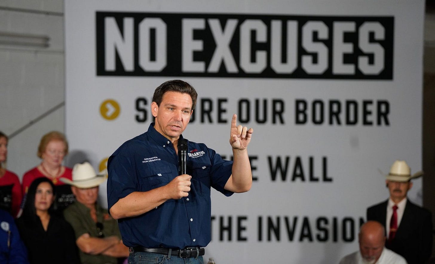 May be an image of 7 people, people standing, belt buckle and text that says 'S NO EXCUSES RE OUR BORDER BONDESANTS DESANTIS WALL THE INVASIO'