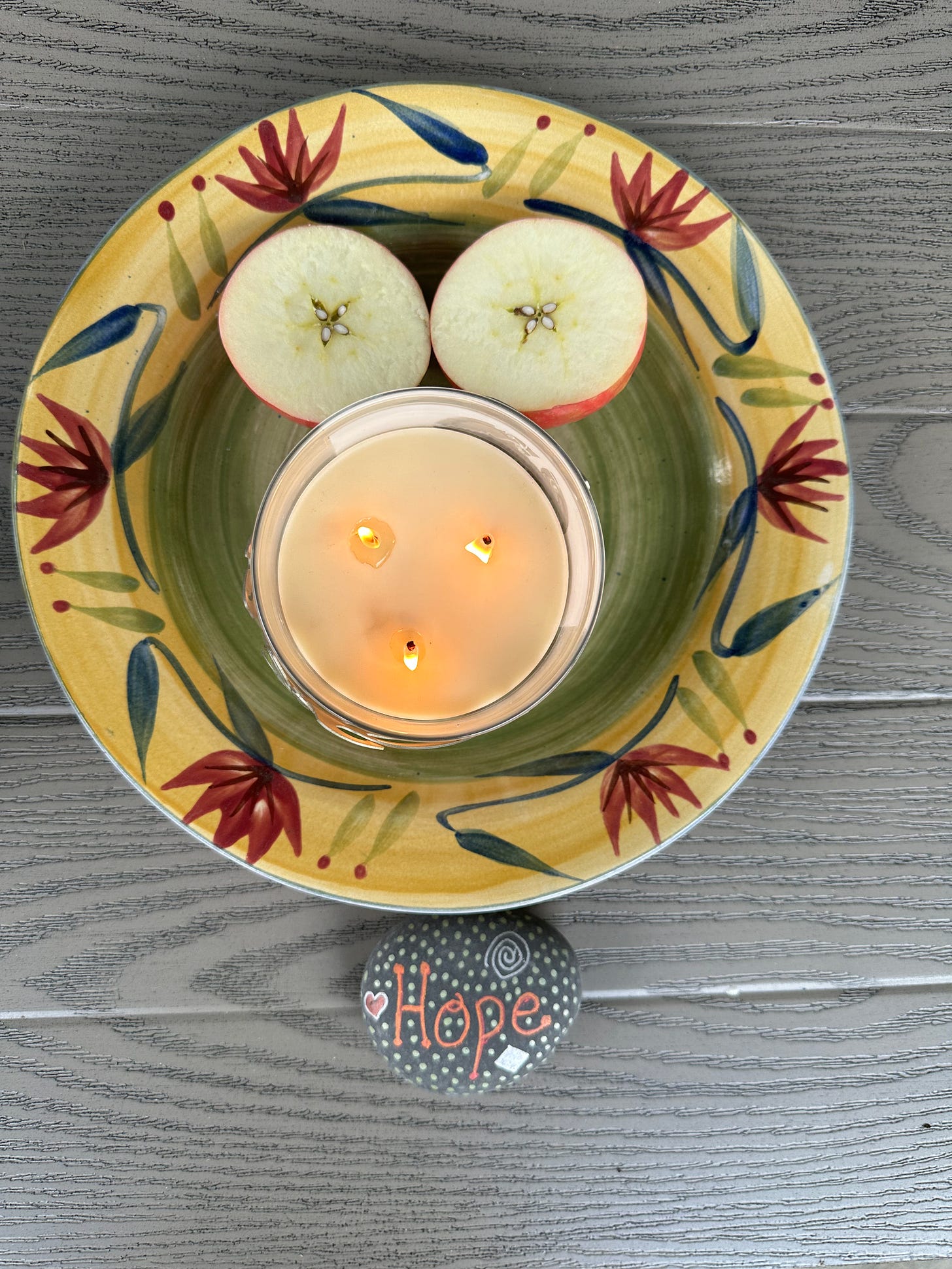 apple cut in half to show 5-pointed star and lit candle. Hope written on a rock.