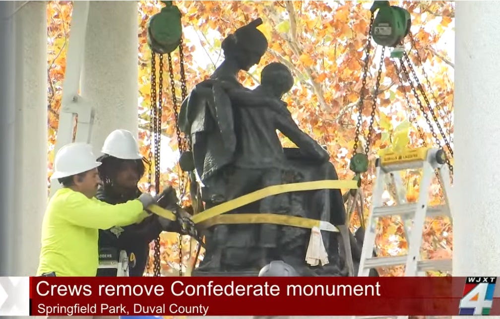 Video screenshot of hardhat-wearing workers preparing to remove Confederate monument in Jacksonville.  The statue has been attached to straps prior to lifting it off its pedestal