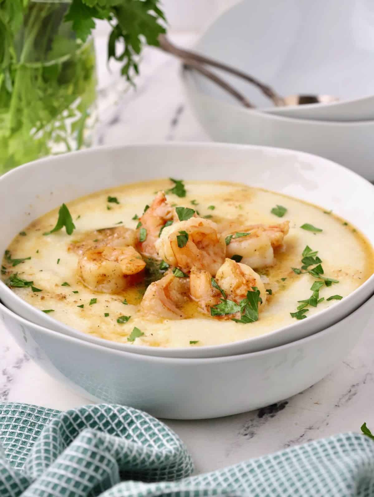Cajun Shrimp and Grits in a white bowl garnished with parsley. 