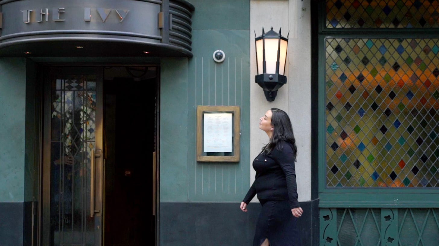 A woman walks in front of The Ivy restaurant entrance
