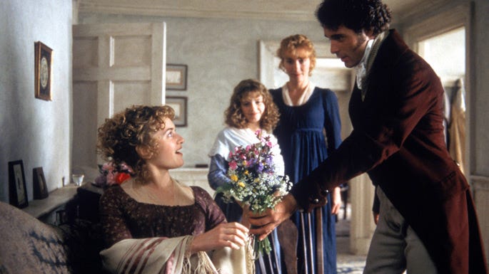 Mr. Willoughby hands flowers to Marianne, who is laying on a couch. 