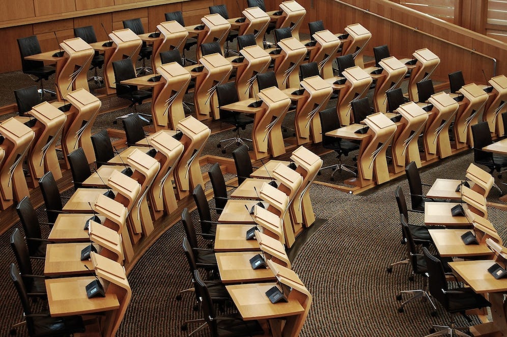 Imagem horizontal das mesas dentro do prédio do parlamento escocês