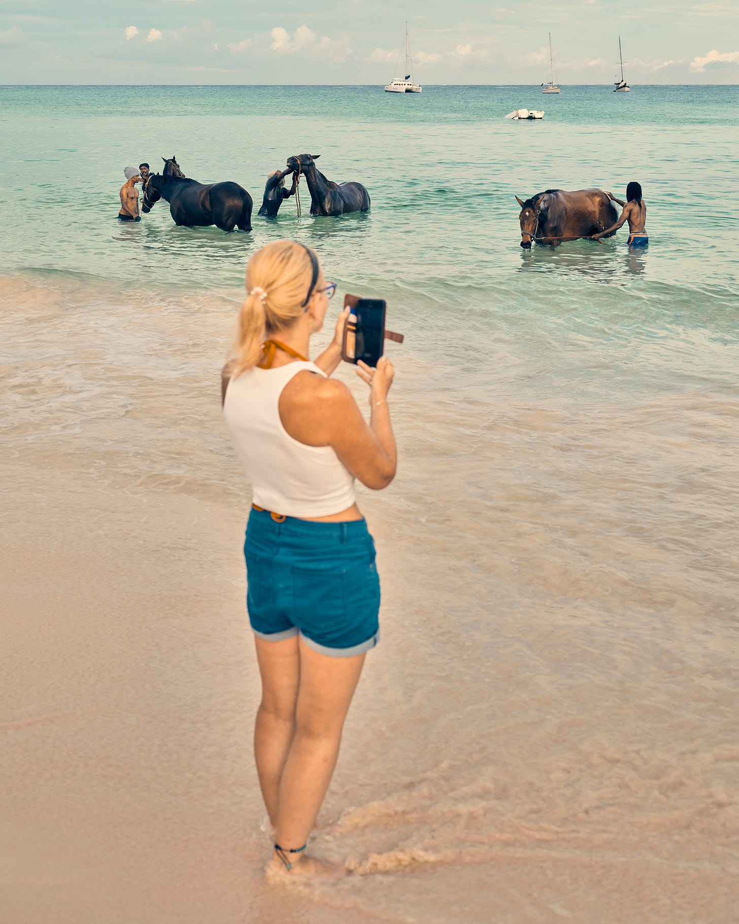 A tourist photographs caretakers bathing racehorses on Pebbles Beach. Horse racing, polo, and cricket are all commonplace in Barbados and a direct inheritance of the British colonial past. (Christopher Gregory-Rivera for TIME)