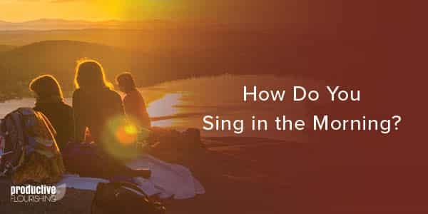 Frieds sit on a rocky ledge watching a sunrise over the water. Text Overlay: How Do You Sing In the Morning?