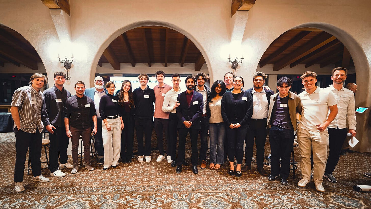 Group photo of student attendees from UCSB’s Gauchos in Business program at the Ventech “AI Impacts & Implications” Summit. The students stand together smiling in a warmly lit venue with arched architecture and a patterned carpet. They are dressed in smart-casual attire, wearing name badges, and represent a diverse group of emerging leaders interested in AI, business, and innovation. Group photo of student attendees from UCSB’s Gauchos in Business program at the Ventech “AI Impacts & Implications” Summit. The students stand together smiling in a warmly lit venue with arched architecture and a patterned carpet. They are dressed in smart-casual attire, wearing name badges, and represent a diverse group of emerging leaders interested in AI, business, and innovation.