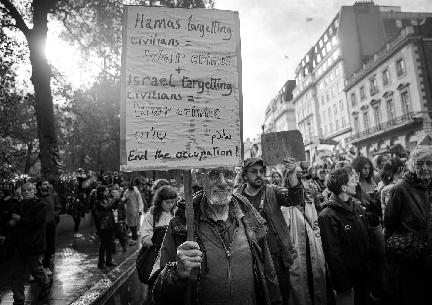 A man with a sign condemning both Israel and Hamas in the current conflict. CC-BY licensed photo by Alisdare Hickson on Flickr: https://www.flickr.com/photos/59952459@N08/53289187680