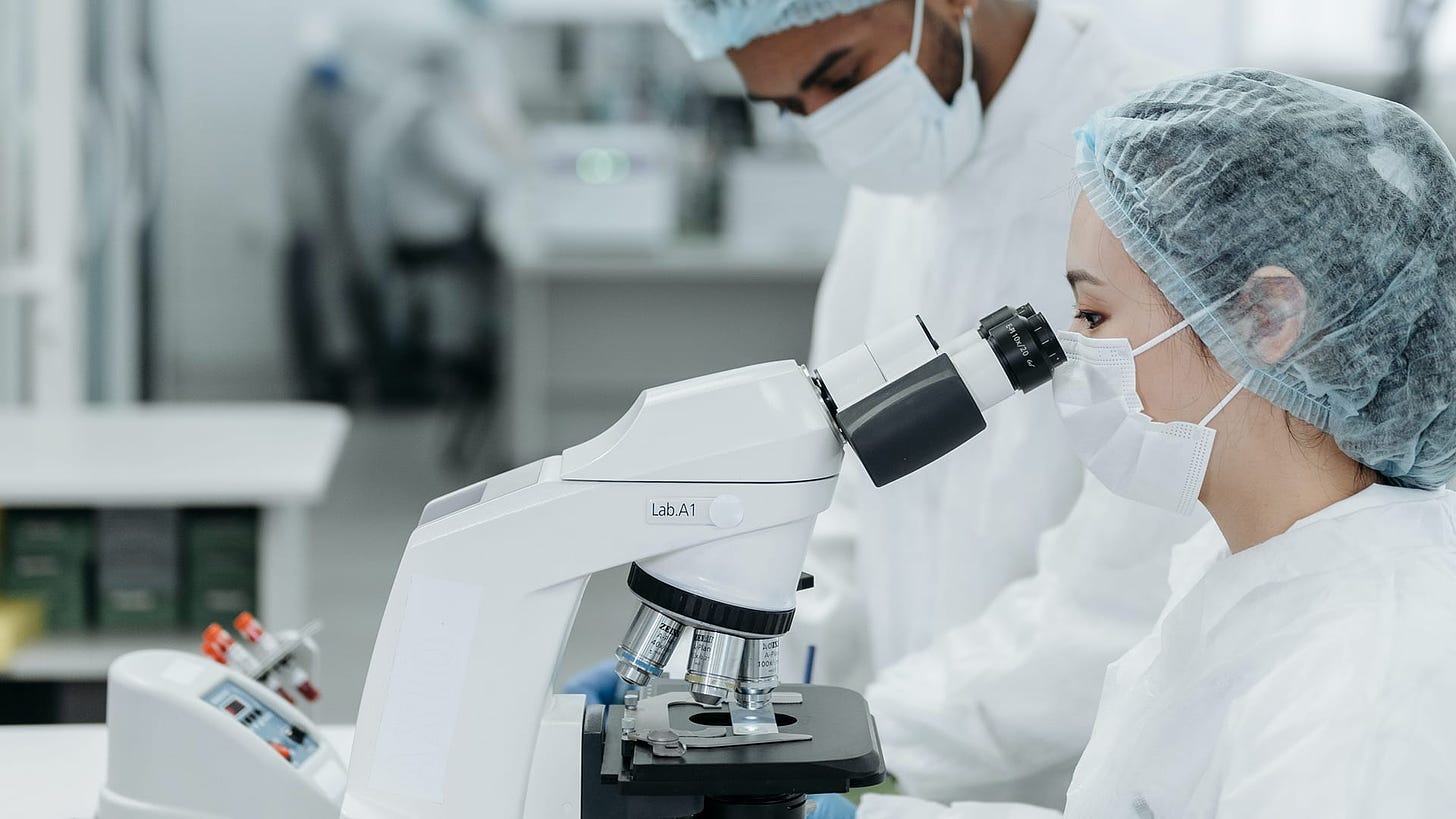 A scientist looks intently through the eyepiece of a laboratory microscope