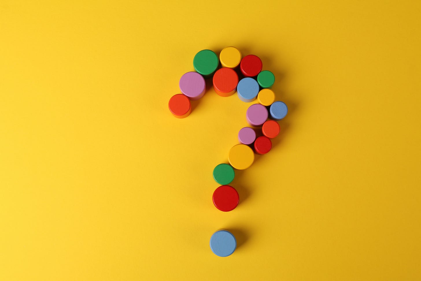 image of a question mark made out of multicolored pegs on a yellow backdrop