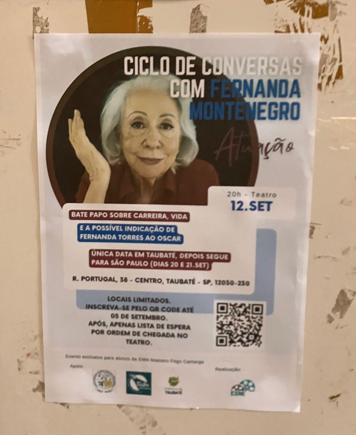 Fotografia de um cartaz a4 impresso e colado num painel. Nele, as informações sobre uma palestra com fernanda montenegro sobre atuação e a indicação de sua filha na cidade de Taubaté