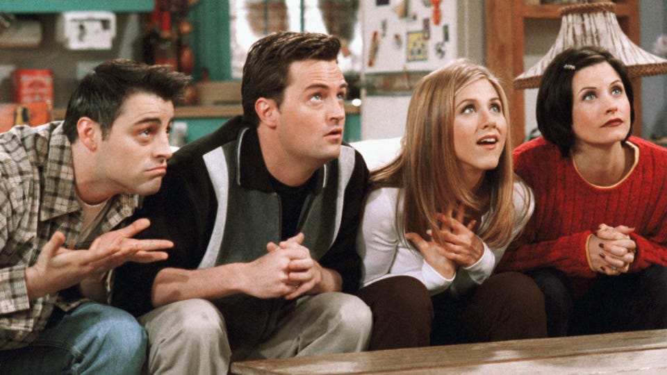 quatro personagem de friends sentado lado a lado: joey, homem branco do cabelo preto; chandler, homem branco do cabelo preto; rachel mulher loura e monica, mulher branca de cabelo preto.