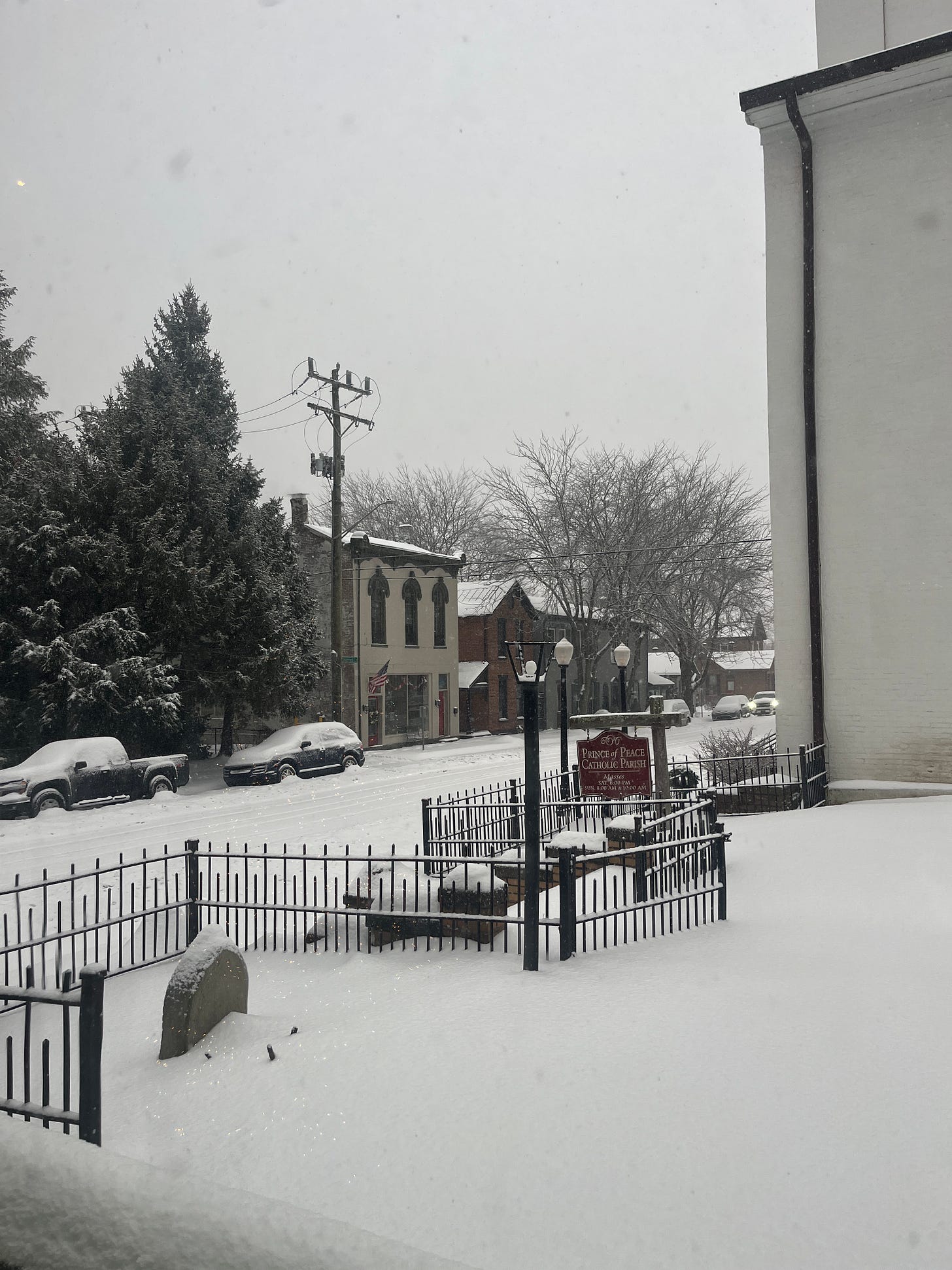 A view into the street outside Robyn's house, with historic buildings across the street and at least 6 inches of snow on the ground with more coming down