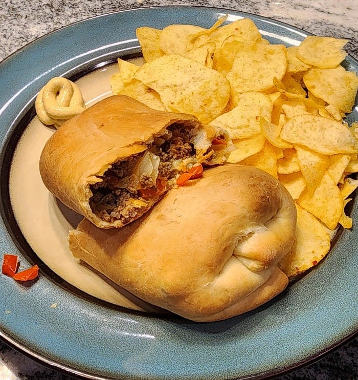 beef and cabbage runza, cut in half on a plate with potato chips