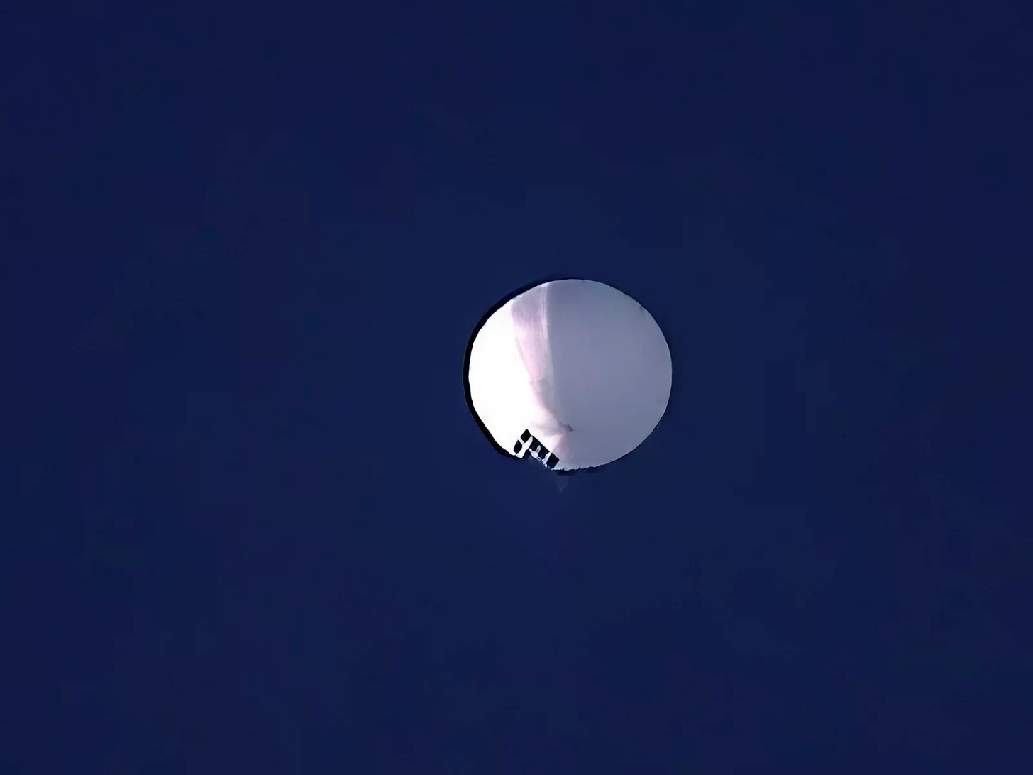 A white sphere against a deep blue sky.